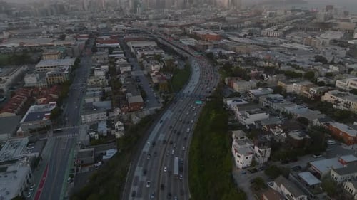 Backwards Fly Above Busy Highway Winding Through Metropolis Tilt Up Reveal of Cityscape with Modern