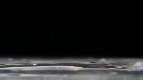 Close up on water drops bouncing on a glassy water surface, copyspace