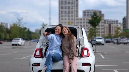 Friends taking a selfie on car in city