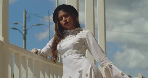 A young girl wearing a vintage wedding gown, standing atop an ancient fort.