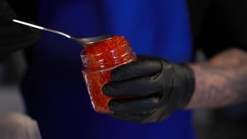 Hand Filling Jar with Delicious Red Caviar