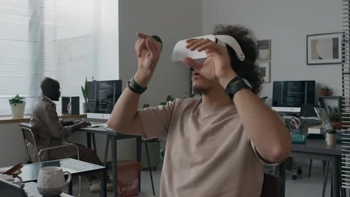 Software Engineer Using VR Headset and Typing on Laptop at Working Desk