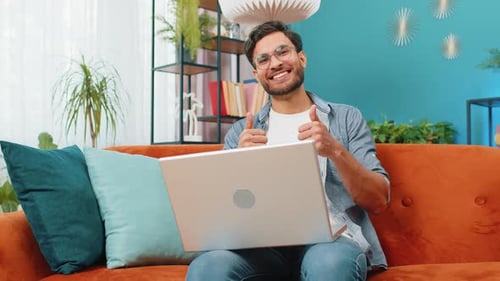 Excited Young Adult Using Laptop at Home