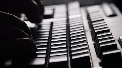 Extreme Closeup of a Hacker Programmer's Hand Typing on a Computer Keyboard in a Dark Room