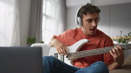 Young Man Plays Bass Guitar at Home
