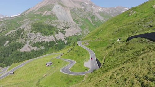 A Scenic Red Car Journey Through Winding Green Mountain Passes
