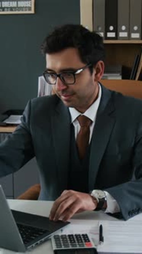 Portrait of Indian Businessman in Three-Piece Suit Sitting at Table in Office