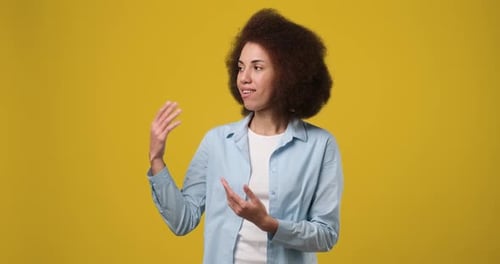 Smiling Woman Presenting and Gesturing on Yellow Background
