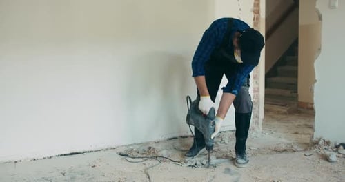 Construction Worker Breaking Concrete Floor with Jackhammer