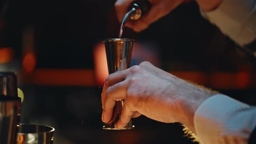 Nahaufnahme: Barkeeper, der Alkohol in einen Messbecher gießt, in der Nachtbar, Hand haltend