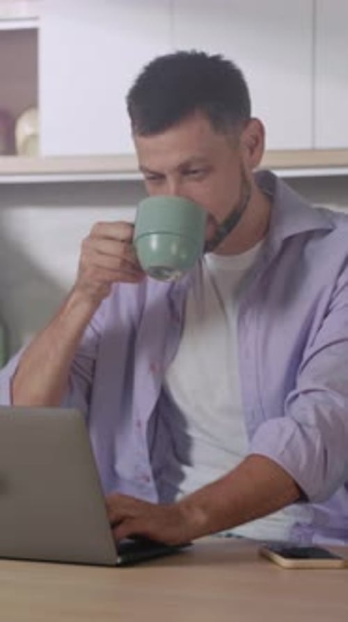 Mann, der bequem arbeitet, fokussierte Person in Freizeitkleidung, die während der Arbeit aus der Ferne mit Kaffee arbeitet