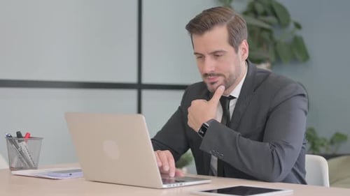 Man in Suit Thinking at Computer in Office