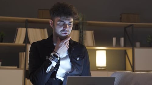 Young Man Using Laptop at Night Indoors
