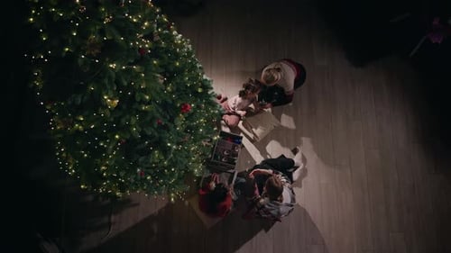 Top View of a Young Woman and a Little Girl Decorating a Christmas Tree with Ornaments and Lights