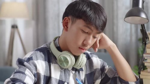 Bored Asian Teenager Studying At Home, Asia Teen Writing While Sitting On The Table