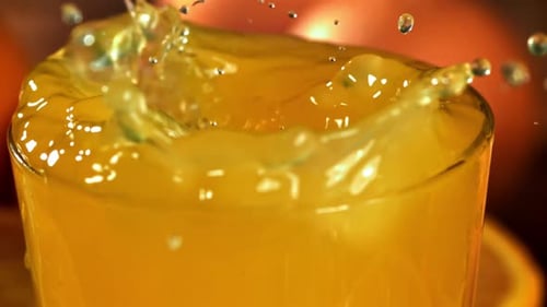 Ice Cubes Splashing into Glass of Orange Juice