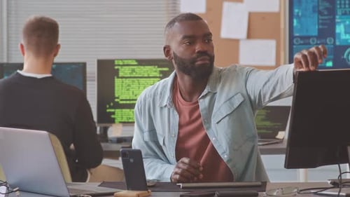 Programador afroamericano trabajando con un colega en la oficina