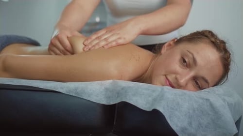 Unrecognized Female Spa Worker Giving Back Massage to Woman Client in Healthcare Clinic
