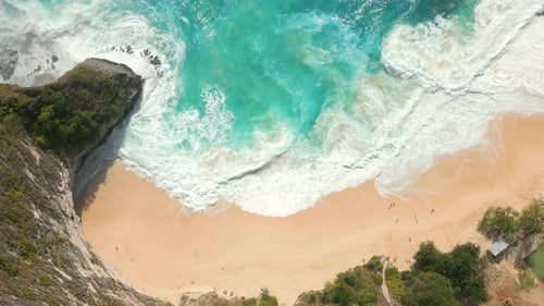 Blick von oben auf die türkisfarbenen Meereswellen, die am abgelegenen Strand und auf den Klippen von Bali zusammenbrechen