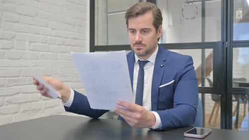 Mature Adult Businessman Reading Documents in Office