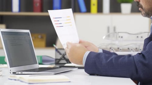 Adult Analyzing Charts at a Modern Workplace