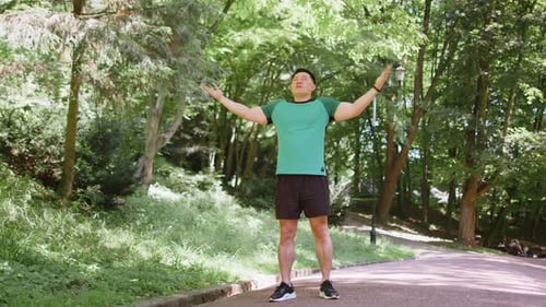 Man Stretching in Green City Park on Sunny Day