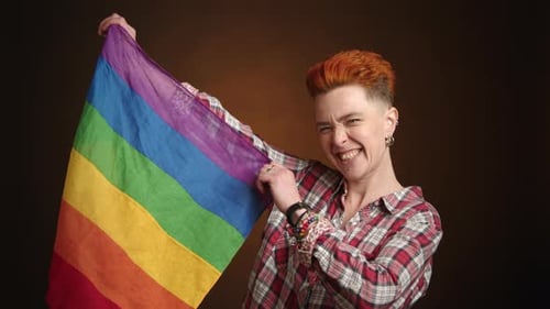 Smiling Person Holds Rainbow Flag in Studio Setting