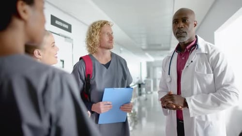Diverse doctors discussing work in corridor at hospital, slow motion