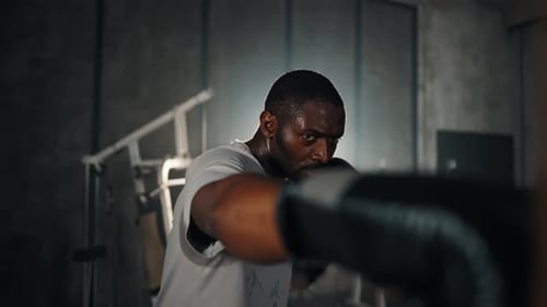 Boxer Training Hitting Punching Bag African American Sweated Sportsman Practicing Punches in Gym