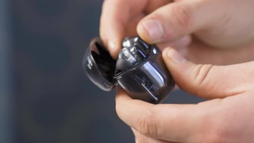 Hands Open Case of Black Wireless Earbuds