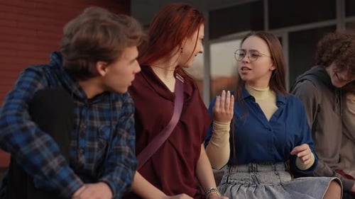 Amigos felizes sentados no parapeito perto da escola