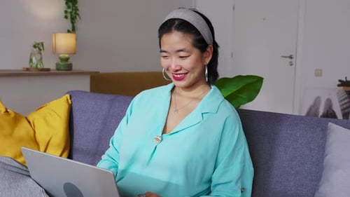 Woman Relaxing on Couch Using Laptop Indoors
