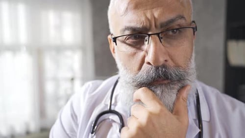 Mature Adult Doctor Thinking in Hospital Office