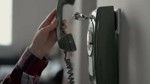 A Person Lifts Receiver of a Vintage Wallmounted Rotary Telephone Classic Communication Retro