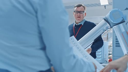 Engineers Discussing Technology with Robotic Arm in Lab