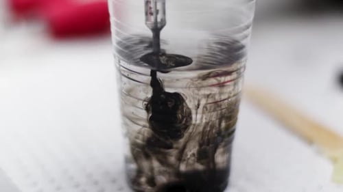 Tätowierer reinigt die Nadel mit Wasser, um die Tintenfarbe zu ändern
