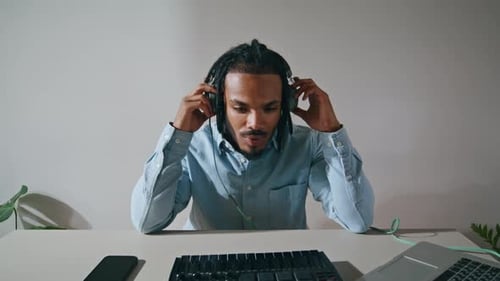 Man with Headphones Using Midi Keyboard at Desk