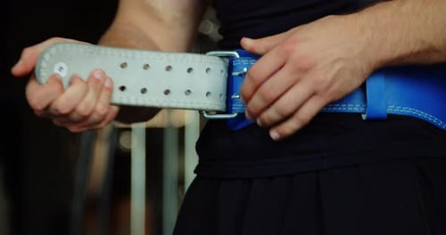 Closeup on Bodybuilder Male Hands Putting Protection Gym Belt for Weight Training Cropped View on