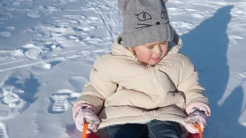Excited Child Girl Enjoys Sledding in Plastic Sleigh on Snow at Sunset Pulled by Father