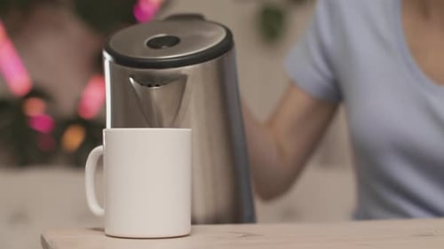 Woman Pouring Hot Water Into White Mug on Table