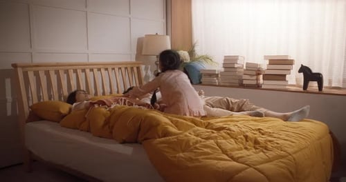 Family Laughing and Playing Together on Bed