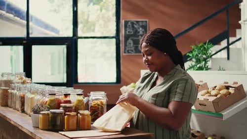 Client Pouring Pasta in Reusable Paper Bags at Zero Waste Store