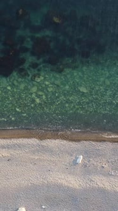 Aerial Vertical View of Beach with Wave Caressing Shore Sun Glare Small Waves on the Water Surface