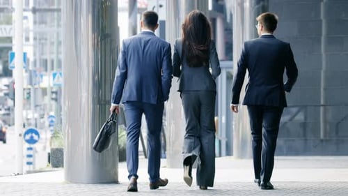 Back View of Three Business People Walking in the Central Business District.