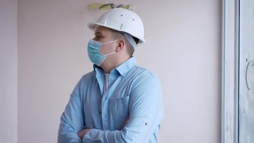 Professional Young Foreman in Covid19 Face Mask Crossing Hands Looking Around Standing in Building