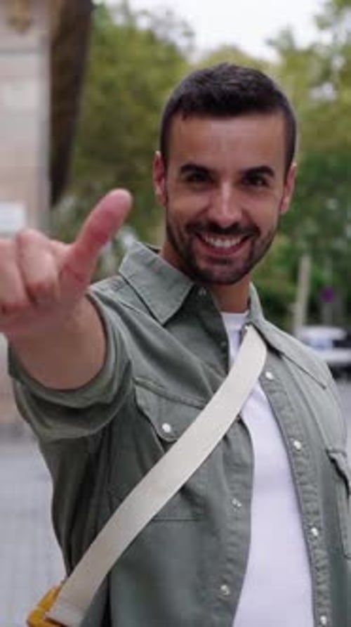 Smiling Man Gives Thumbs Up Gesture on City Street
