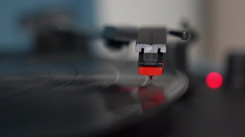 Close-up shot of a vinyl record spinning on a turntable with stylus arm in focus. Vintage analog aud