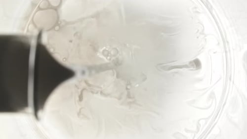 Liquide versé dans un bécher avec de l'eau provenant d'un flacon en verre sur fond blanc The Medicine Concept