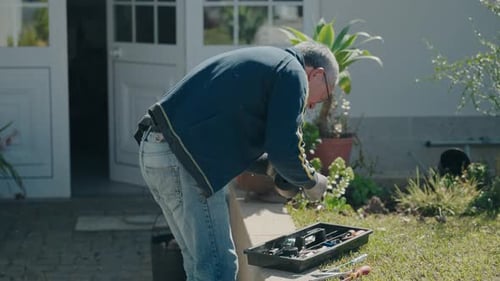 Man using tools from toolbox while repairing in house garden