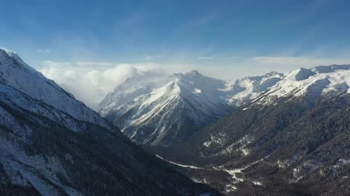 Air flight through mountain clouds over beautiful snow-capped peaks of mountains and glaciers.